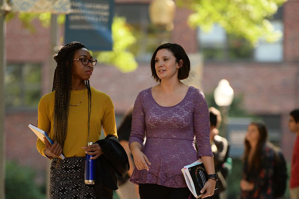 Two people talking and walking through GW's campus on a sunny day
