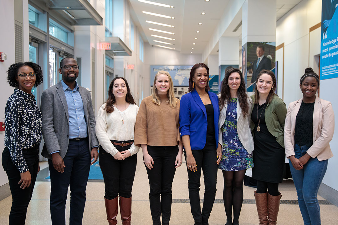 A group of TSPPPA students standing in a line inside a GW building and smiling at the camera