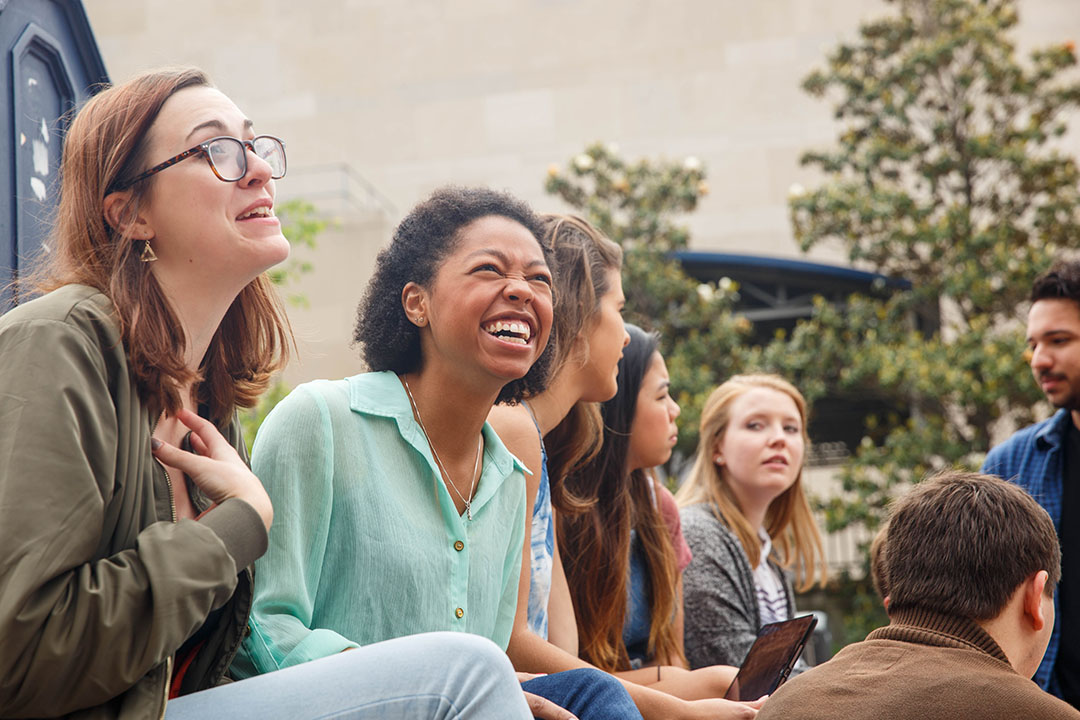 Group of students in Kogan Plaza sitting and laughing