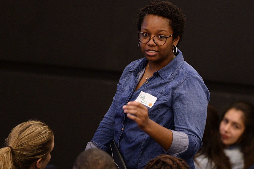 Erica Ross wearing a nametag and speaking to a roomful of seated students