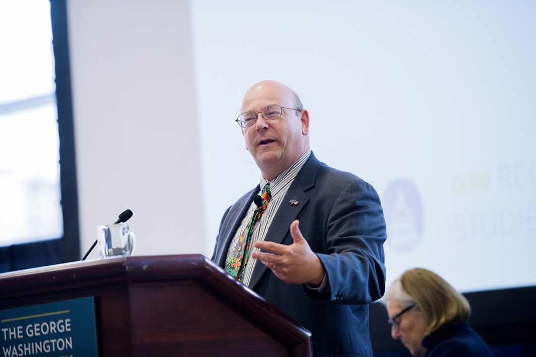Jerry Ellig speaking at a podium with a George Washington University sign