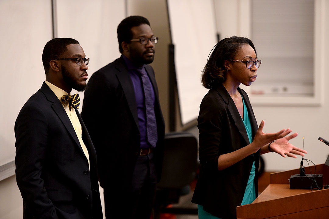 Members of the MLP standing at the front of a classroom and talking