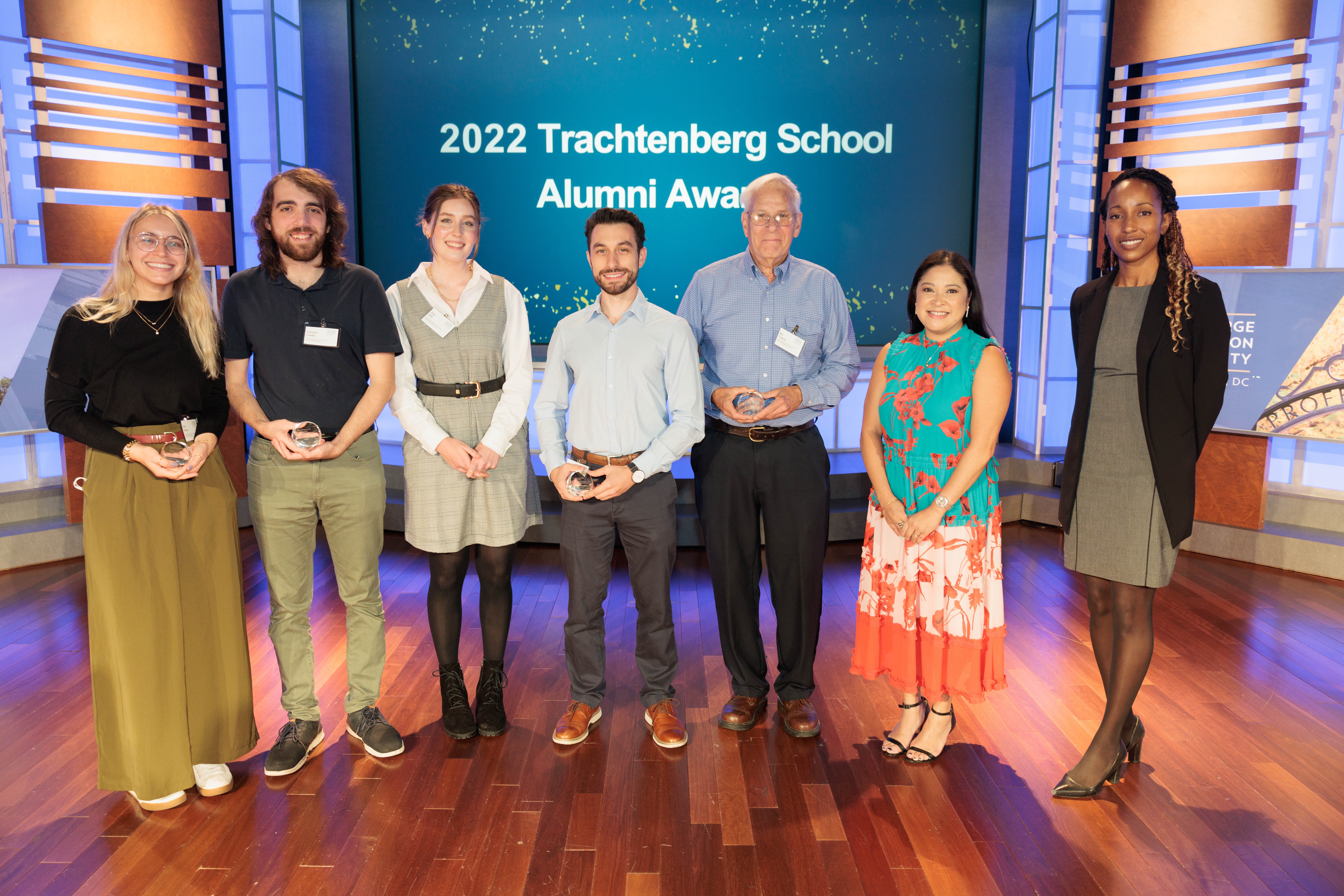 Group of people in business attire standing on the rooftop of a DC building with the Washington Monument in the background