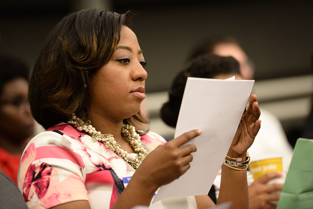 A woman seated during an orientation session reading a stack of papers